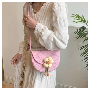 Side view of pink woven saddle bag with 3D yellow flowers on a model in a white dress