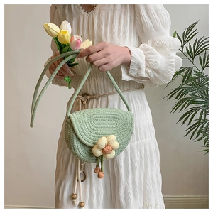 Close-up of light green knit crossbody bag with woven flower and spiral texture