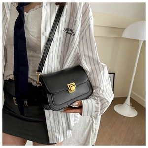 Detail of a vintage black leather square bag with elegant golden metallic square clasp