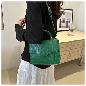 Detail of green crocodile pattern handbag with twisted handle in a minimalist setting