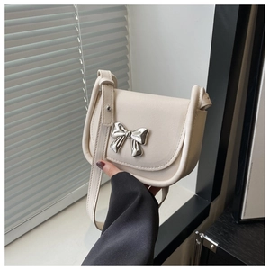Détail d'un sac bandoulière en cuir beige avec un fermoir nœud papillon argenté