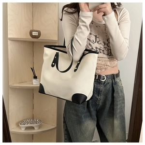 Detalle de un bolso tote minimalista en blanco y negro mostrado en una selfie de espejo