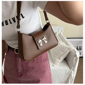 Detailed shot of brown PU leather shoulder bag with a silver bow metal buckle detail