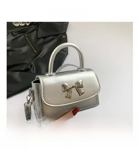 Detailed close-up of metallic silver mini bag featuring a decorative metal bow and top handle