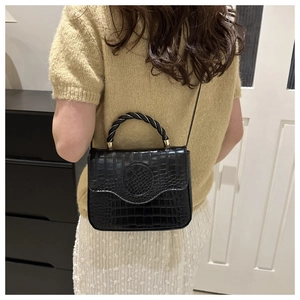 Close-up of black crocodile pattern handbag with unique twisted black and gold handle