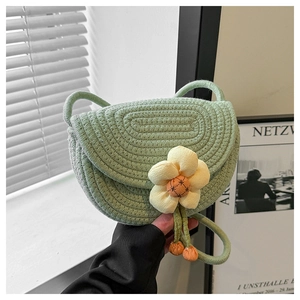 Close-up of light green woven shoulder bag featuring a decorative yellow fabric flower