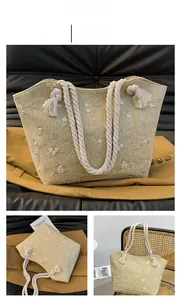 Close-up of beige woven tote bag with floral embroidery and thick rope handles