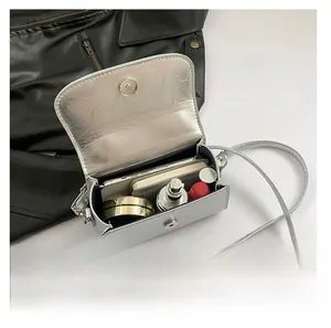 Silver mirror mini crossbody bag interior showing phone, perfume, and lipstick capacity