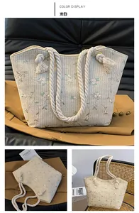 Close-up of beige straw tote bag with floral embroidery and cotton rope fringe handles
