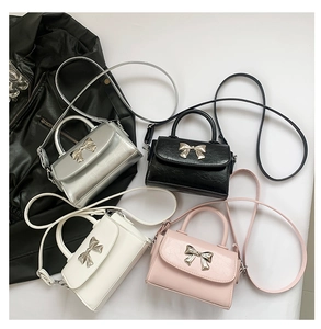 Overhead view of mini bow bags in silver, black, white, and pink with metal bow detail
