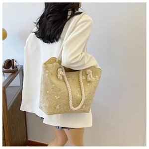 Close-up of woven straw tote bag with floral embroidery and cotton rope handles
