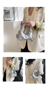 Macro detail of silver pleated cloud bag featuring a unique knotted handle and heart charm