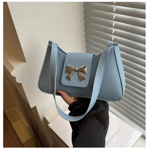 Close-up of light blue underarm bag featuring a metallic silver bow buckle detail