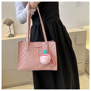 Detail of pink plaid tote bag featuring a leather fashion label and peach plush charm