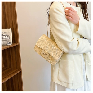Detail of hand-woven straw saddle bag featuring floral lace embroidery and gold metal clasp