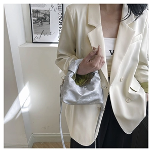 Detail of silver pleated cloud bag with metallic finish shown on a model