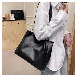 Close-up of matte black large tote bag showing geometric stitching and leather texture