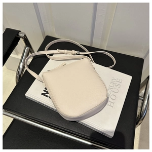 Close-up of off-white lychee grain leather square bag with adjustable strap and buckle