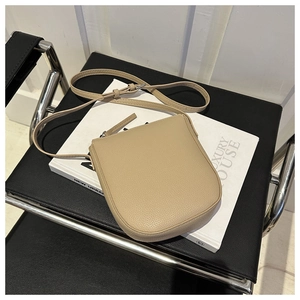 Detail of a beige pebbled leather shoulder bag placed on a book in a luxury setting