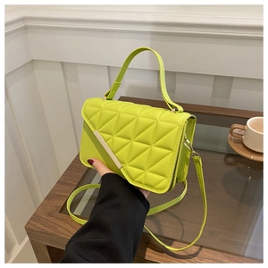 Macro detail of quilted neon green handbag with gold metallic trim and texture