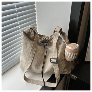 Dettaglio della borsa tote in nylon beige con coulisse, tracolla larga e ciondolo caffè
