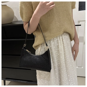 Borsa hobo nera con paillettes indossata a spalla con finitura lucida e cinturino sottile