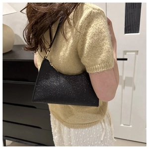 Vista a spalla di una borsa hobo nera con paillettes, cinturino in pelle e glitter argento