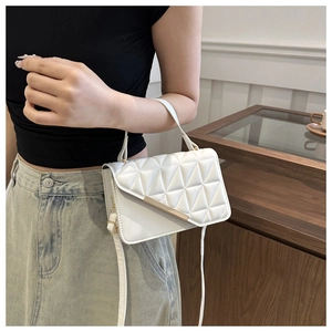 Detail of white quilted flap bag with gold metal trim and adjustable leather shoulder strap