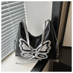 Detail of silver butterfly patch on black leather shoulder bag with natural lighting