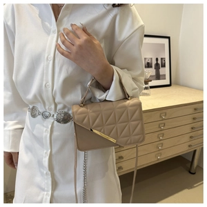 Detailed view of beige quilted handbag with geometric pattern and gold metal hardware trim