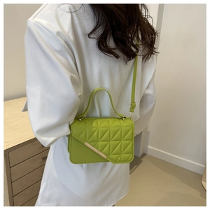 Detail of bright green quilted crossbody bag with gold metal trim and top handle
