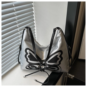 Close-up of silver metallic bucket bag featuring large black butterfly applique and drawstring