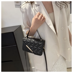 Close-up of black quilted leather crossbody bag with elegant gold metal hardware detail