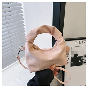 Close-up of pink pleated dumpling bag with knot handle and detachable shoulder strap