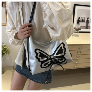 Detail of silver Y2K mirror shoulder bag featuring a black butterfly and ribbon design