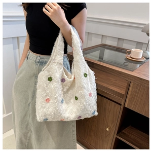 Detail of white fluffy tote bag with colorful floral embroidery and soft plush texture