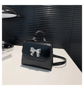 Detail of black bow-knot handbag featuring glossy PU leather and silver metal buckle
