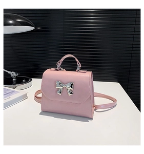 Detailed view of pink mini square bag featuring a large silver mirrored metal bow decoration