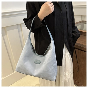 Detail of light blue faux suede hobo bag with round lines and minimalist logo patch