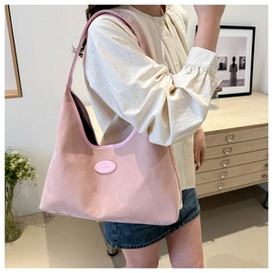 Close-up of pink minimalist underarm bag with brand logo shown on a model