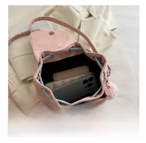 Pink leather backpack interior showing capacity for smartphone and wallet with fuzzy charm