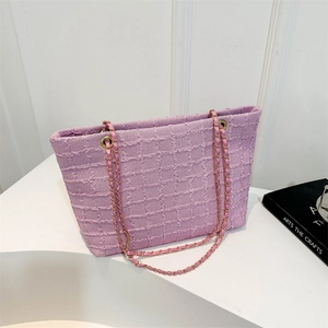Sac fourre-tout en tweed lilas avec bandoulière en chaîne dorée sur surface minimaliste