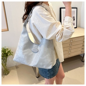 Detailed side view of light gray minimalist tote bag worn by model in home setting