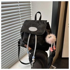 Close-up of black nylon mini backpack with drawstring detail and cute plush charm