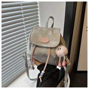 Detail of grey mini bucket bag featuring pink drawstring and plush monster keychain charm
