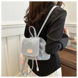 Detail of light blue mini bucket backpack featuring drawstring closure and pompom charm