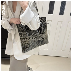 Close-up of black tote bag with gold crocodile texture showing large capacity and strap
