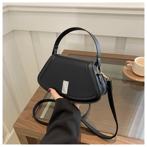 Detail of a chic black trapezoid crossbody bag with silver hardware and top handle
