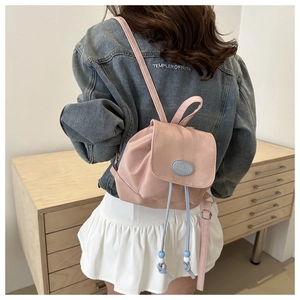 Detail of pink mini backpack with blue drawstring closure and bead accents on model