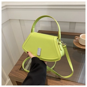 Neon green crossbody bag with silver buckle held in a trendy cafe lifestyle setting